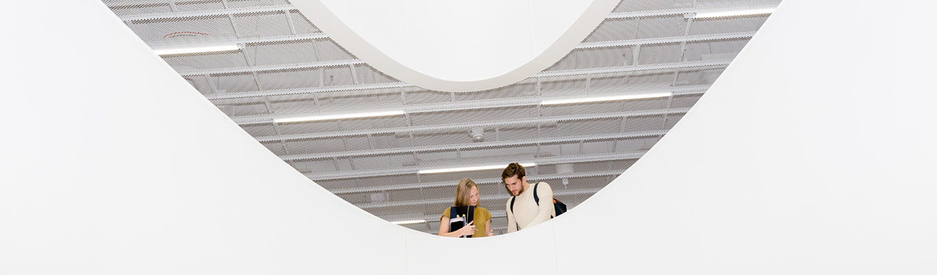 Two people talking under a curved white ceiling structure